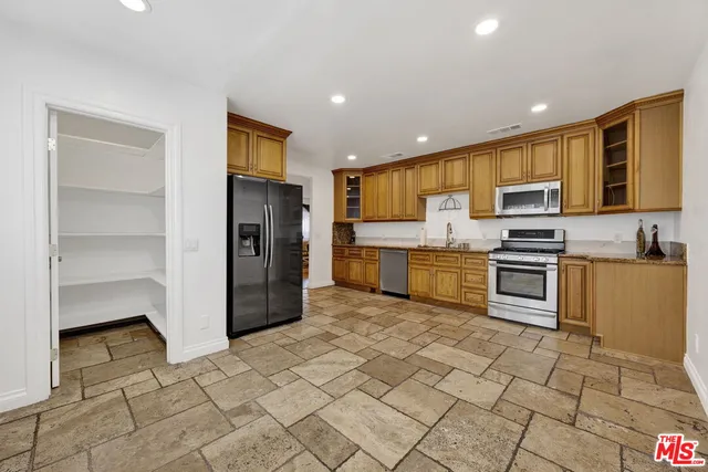 a kitchen with stainless steel appliances granite countertop a refrigerator and a stove top oven