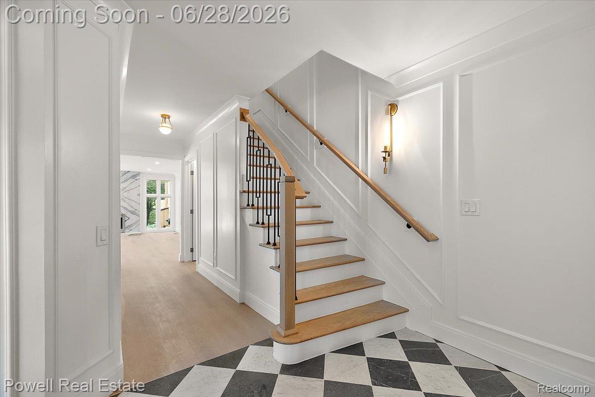 1447 Ravineview Court, Unit C12 Bloomfield Hills, MI 48304 - Photo 9 of 49 Entry foyer featuring a checkerboard tile floor, a curved hardwood staircase with wrought iron balusters, and wainscoting