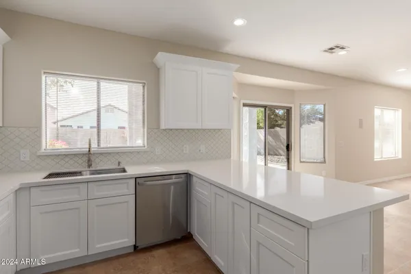 a kitchen with white cabinets and sink