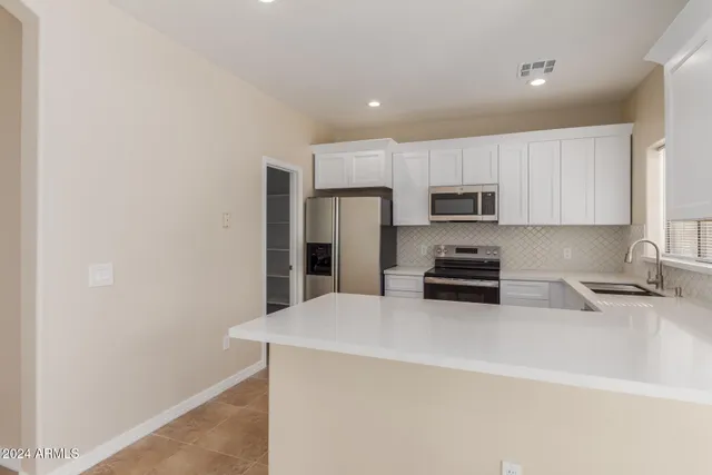 a kitchen with white cabinets and sink