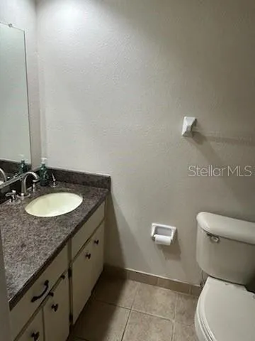 a bathroom with a granite countertop sink and a toilet