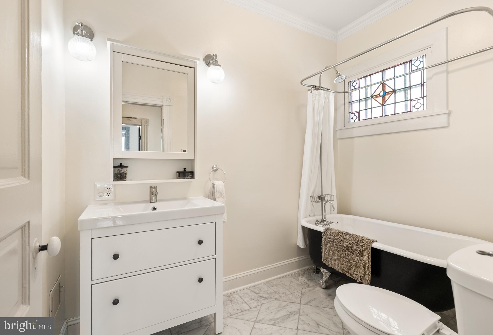 4916 40th Place Hyattsville, MD 20781 - Photo 38 of 48 a bathroom with a toilet a sink a mirror a window and vanity
