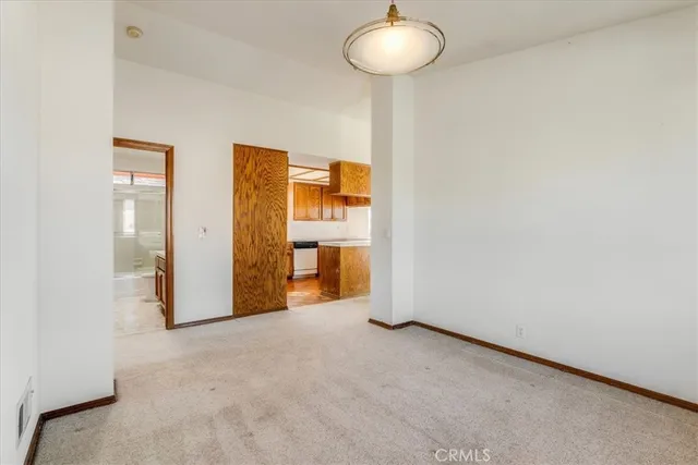 an empty room with chandelier fan and windows