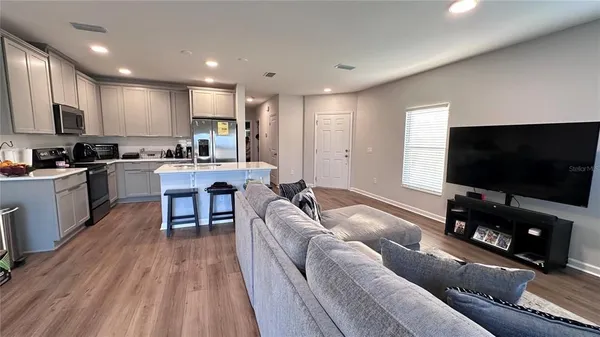a living room with stainless steel appliances furniture and a flat screen tv