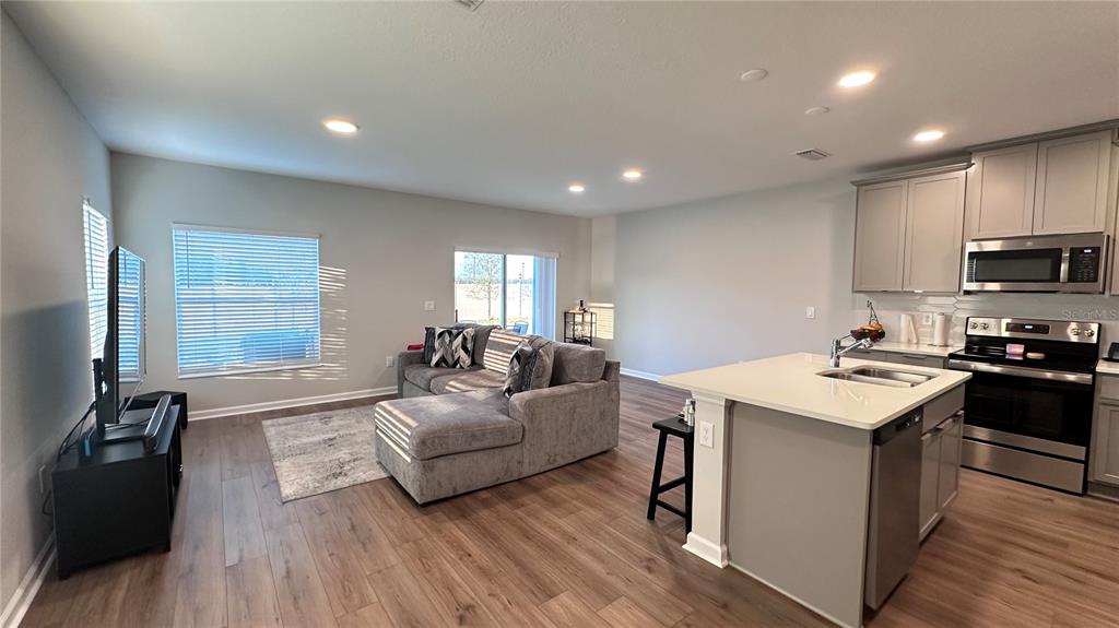 4424 Campsite Loop Orlando, FL 32824 - Photo 7 of 40 a living room with stainless steel appliances kitchen island granite countertop a stove a sink a refrigerator and cabinets with wooden floor