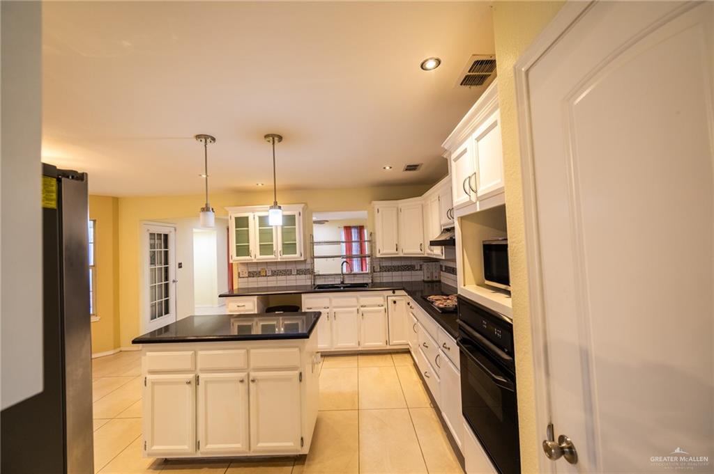 1901 Duke Avenue McAllen, TX 78504 - Photo 11 of 44 Kitchen with a kitchen island, decorative light fixtures, white cabinetry, light tile patterned floors, and black appliances
