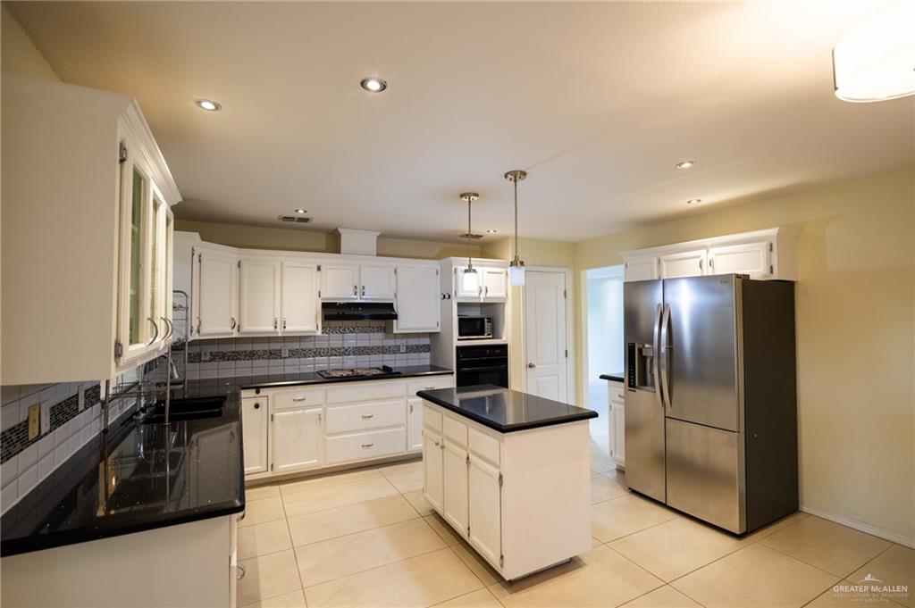 1901 Duke Avenue McAllen, TX 78504 - Photo 14 of 44 Kitchen with white cabinetry, hanging light fixtures, a kitchen island, and black appliances
