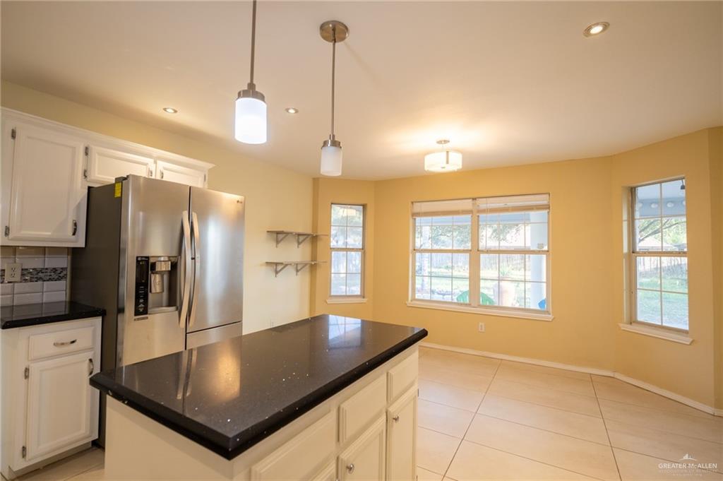 1901 Duke Avenue McAllen, TX 78504 - Photo 16 of 44 Kitchen with white cabinetry, decorative light fixtures, a center island, and stainless steel refrigerator with ice dispenser