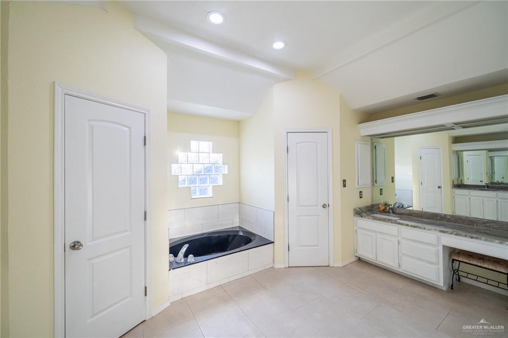 1901 Duke Avenue McAllen, TX 78504 - Photo 28 of 44 Bathroom with vanity, tile patterned flooring, vaulted ceiling, and a washtub