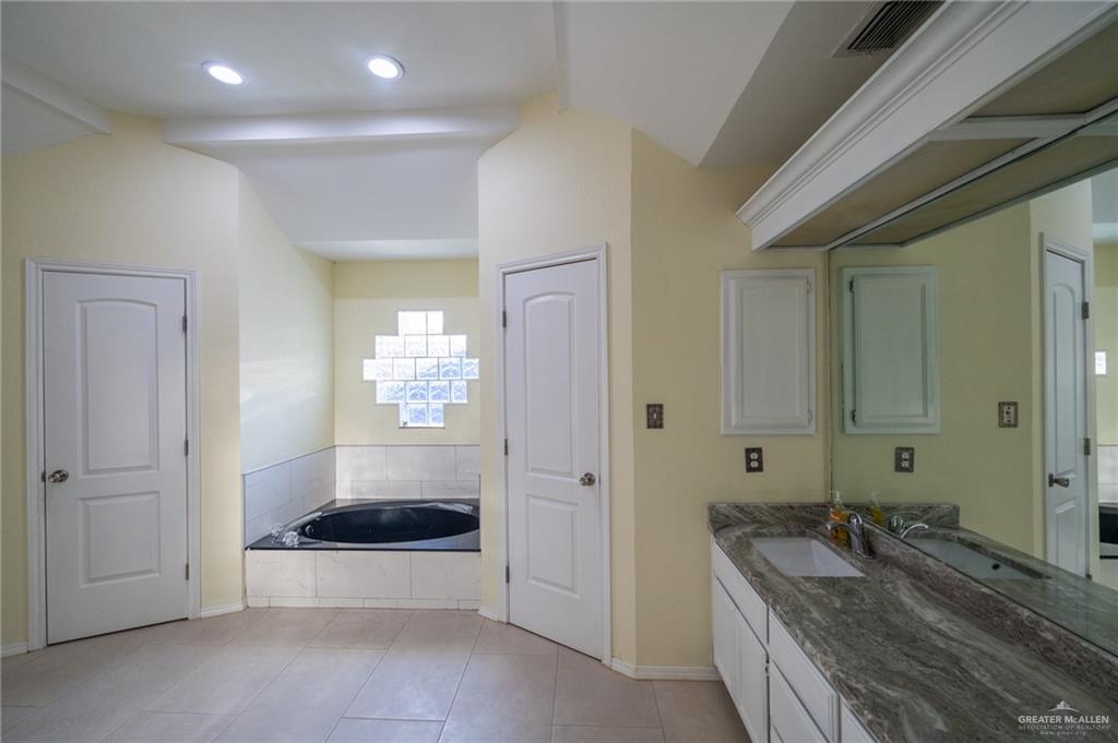 1901 Duke Avenue McAllen, TX 78504 - Photo 30 of 44 Bathroom featuring vanity, vaulted ceiling, tiled bath, and tile patterned floors