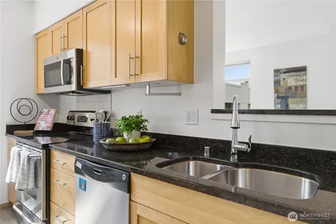 a kitchen with granite countertop a sink stainless steel appliances and cabinets