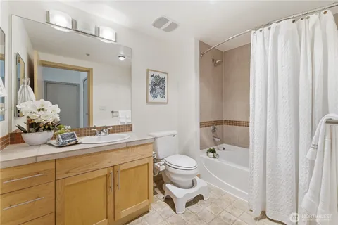 a spacious bathroom with a granite countertop sink toilet mirror and a bathtub