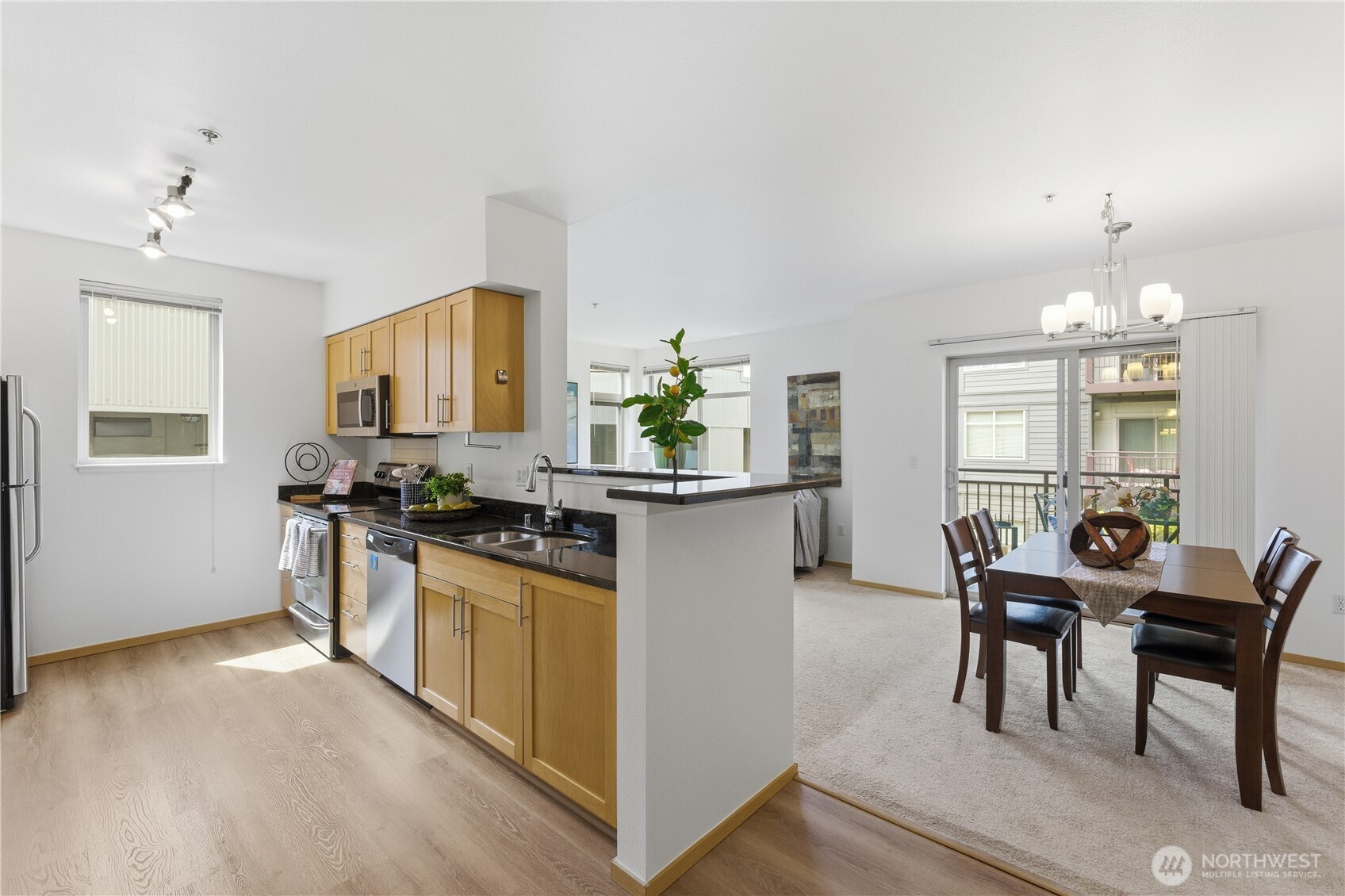3333 Wallingford Avenue North, Unit 203 Seattle, WA 98103 - Photo 5 of 37 a kitchen with stainless steel appliances granite countertop a stove top oven a sink a dining table and chairs with wooden floor