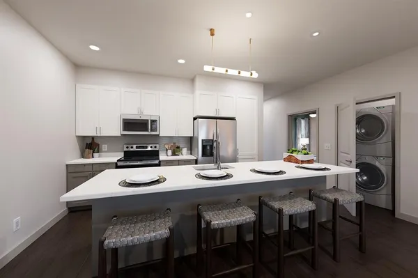 a kitchen with stainless steel appliances kitchen island granite countertop a table chairs stove and white cabinets