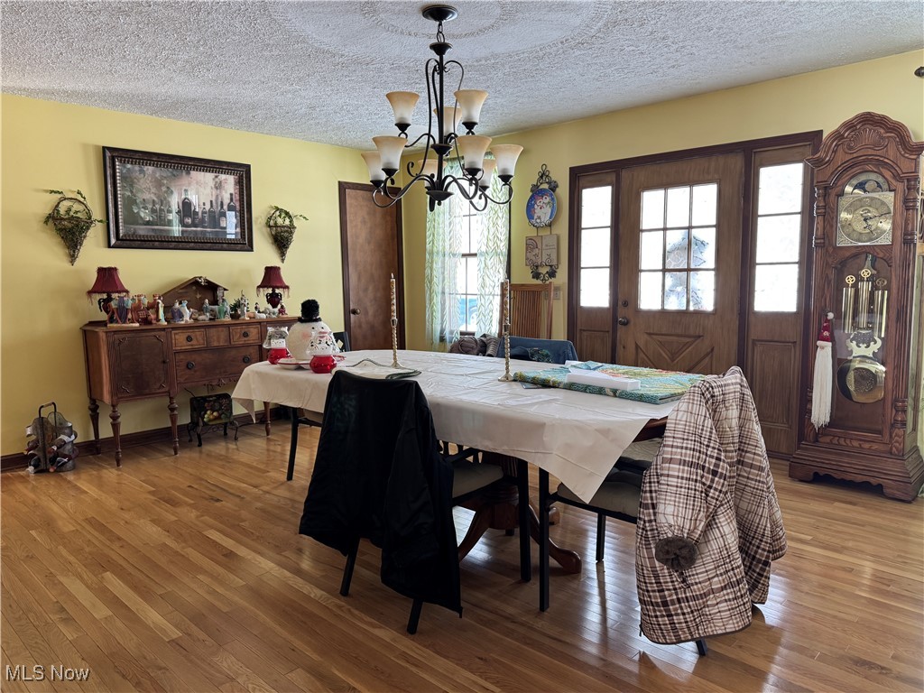 10004 Candy Road Cambridge, OH 43725 - Photo 17 of 20 Dining room with light wood finished floors, a textured ceiling, and a chandelier