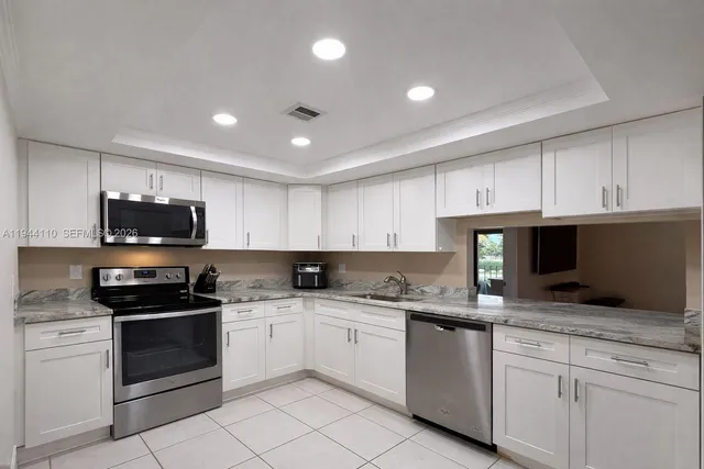 a kitchen with granite countertop white cabinets sink and stainless steel appliances