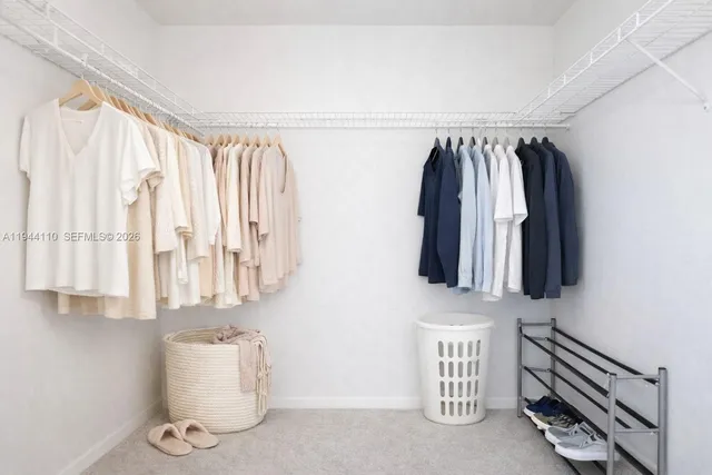 a walk in closet with clothes and shoes