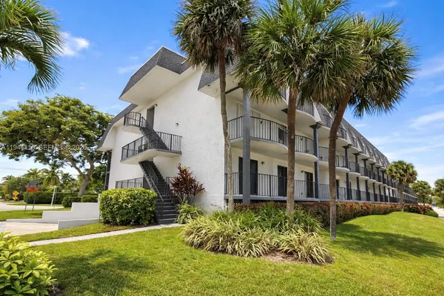 front view of a house with a yard and palm trees