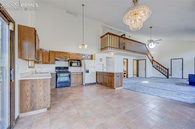 18715 Spring Valley Road Monument, CO 80132 - Photo 12 of 35 Kitchen with light tile patterned flooring, black electric range, a high ceiling, and white refrigerator with ice dispenser