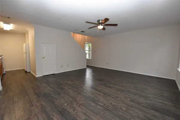 an empty room with wooden floor chandelier fan and windows