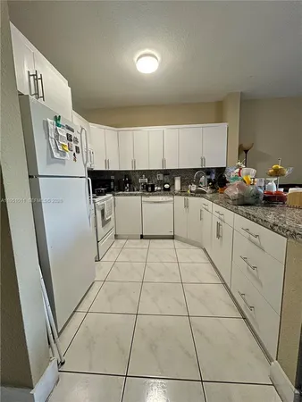 a kitchen with a sink a refrigerator and cabinets