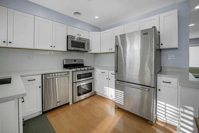 a kitchen with cabinets stainless steel appliances and wooden floor
