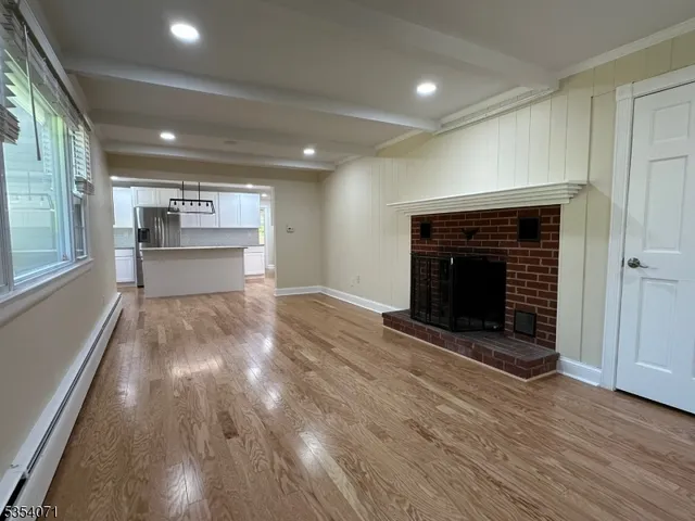 an empty room with wooden floor a fireplace and windows