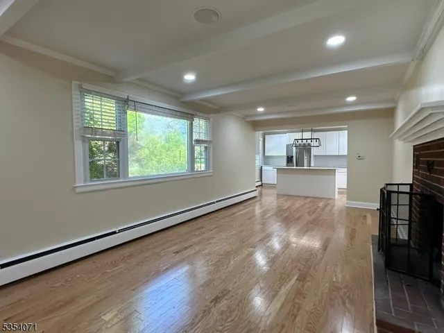 a view of empty room with wooden floor and window