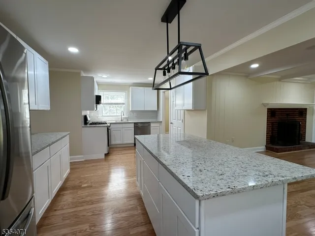 a kitchen with stainless steel appliances granite countertop a sink a counter space cabinets and wooden floor