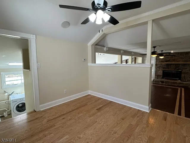 a view of an empty room with window and wooden floor