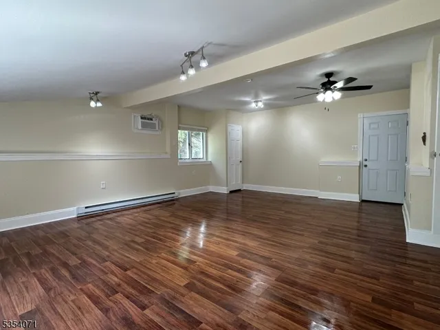 an empty room with wooden floor chandelier fan and windows