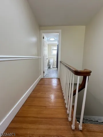 a view of a hallway with wooden floor and stairs