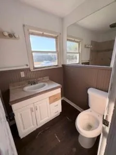 a bathroom with a granite countertop toilet sink and mirror