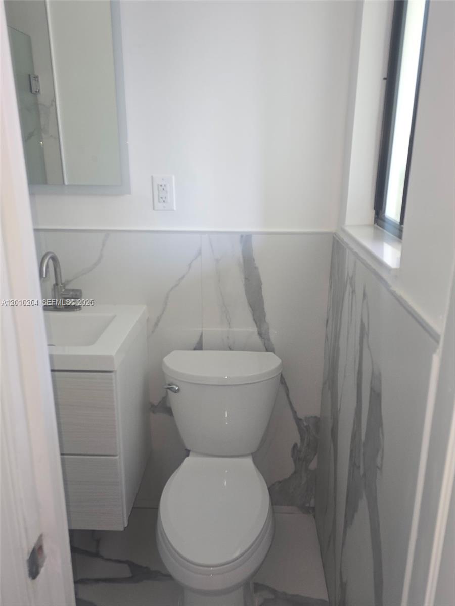 3300 Southeast 6th Street, Unit 2 Pompano Beach, FL 33062 - Photo 6 of 7 a white toilet sitting next to a white sink and vanity