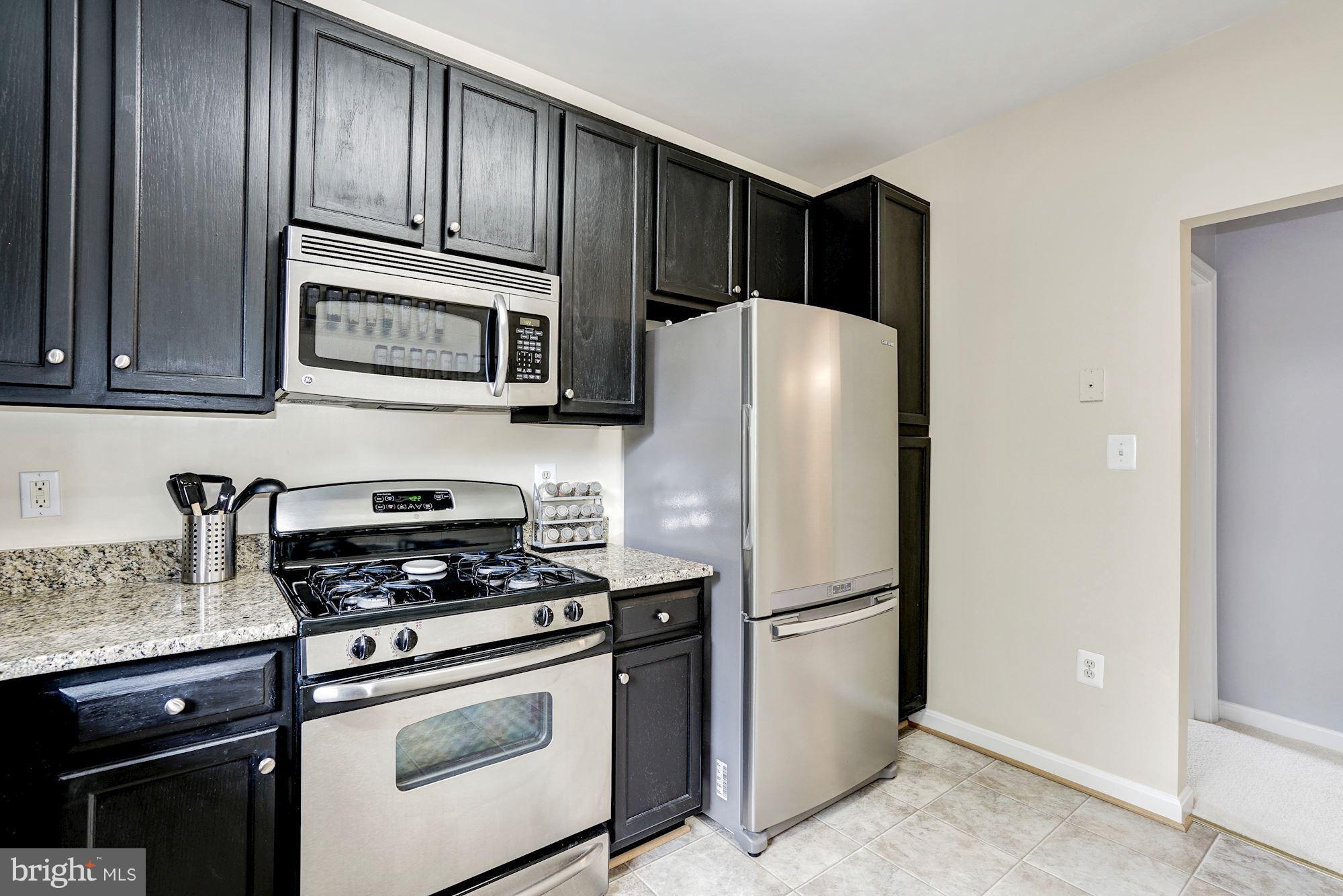 11408 Gate Hill Place, Unit 116 Reston, VA 20194 - Photo 8 of 28 a kitchen with granite countertop wooden cabinets and stainless steel appliances