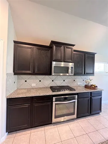 a kitchen with stainless steel appliances granite countertop a stove microwave and cabinets