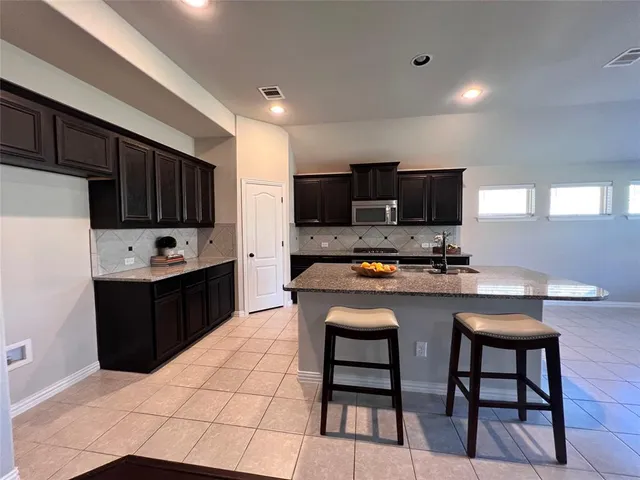 a kitchen with stainless steel appliances a stove a sink dishwasher a refrigerator a microwave oven with granite countertops and cabinets