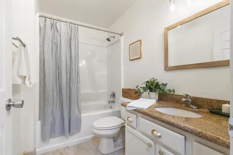 a bathroom with a granite countertop sink toilet and shower