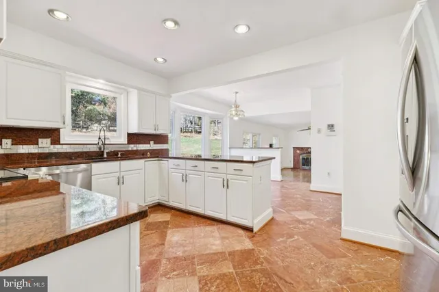 a large kitchen with kitchen island a large counter top space a sink stainless steel appliances and cabinets