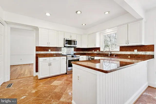 a kitchen with stainless steel appliances granite countertop a sink a stove a refrigerator a center island and cabinets