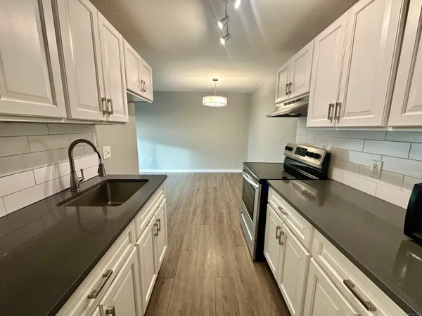 a kitchen with stainless steel appliances granite countertop a sink a stove and cabinets