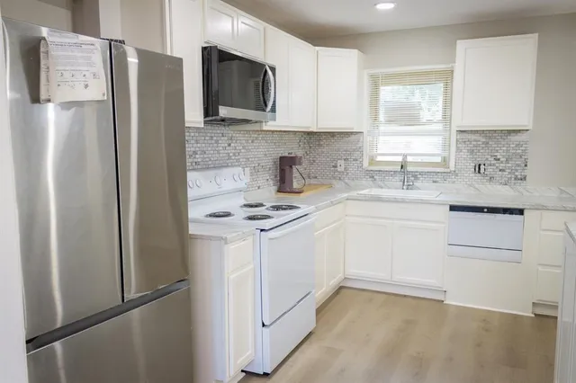 a kitchen with a refrigerator sink and white cabinets