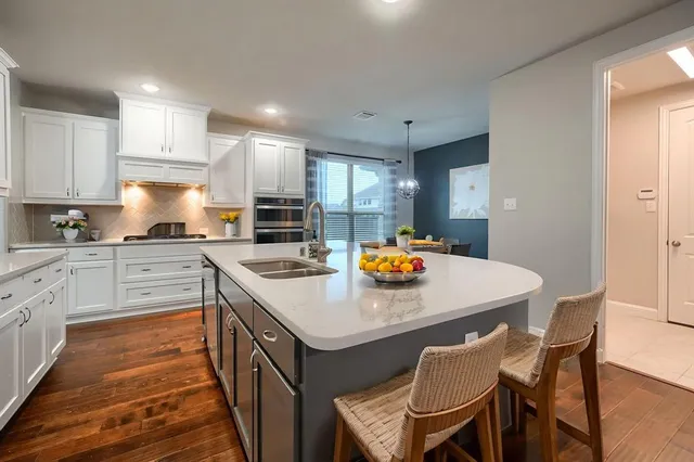 a kitchen with a sink a stove a refrigerator and white cabinets
