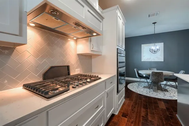 a kitchen with a sink a microwave a stove and white cabinets