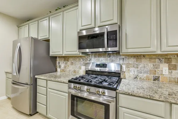 a kitchen with stainless steel appliances granite countertop a stove microwave and refrigerator
