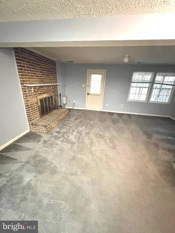 a view of an empty room with wooden floor and windows
