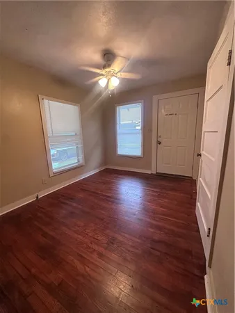 a view of an empty room with window and wooden floor