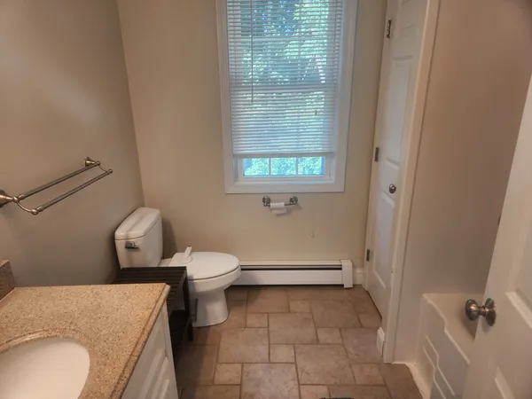 a bathroom with a granite countertop toilet and a sink