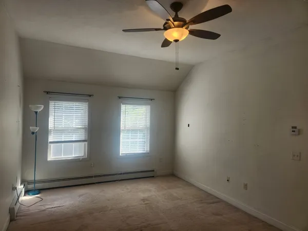 an empty room with windows and fan