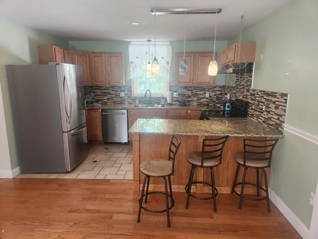 a kitchen with stainless steel appliances granite countertop a refrigerator a sink a stove a dining table and chairs